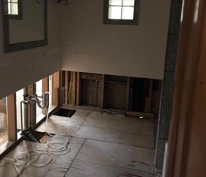 image of bathroom with 3 foot cuts up the drywall and unfinished flooring