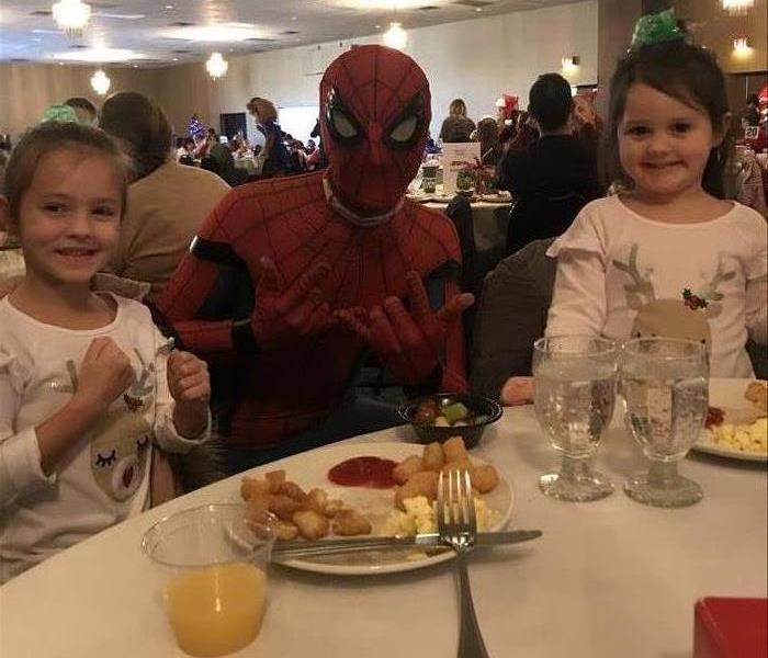 Spiderman character posing with two small children while eating breakfast