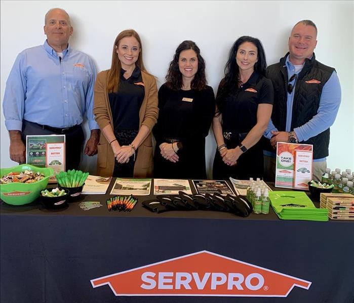 Group of SERVPRO employees behind promotional table at event
