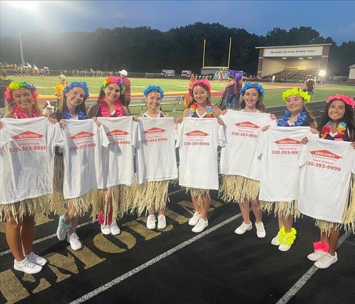 cheerleading squad holding up servpro t shirts