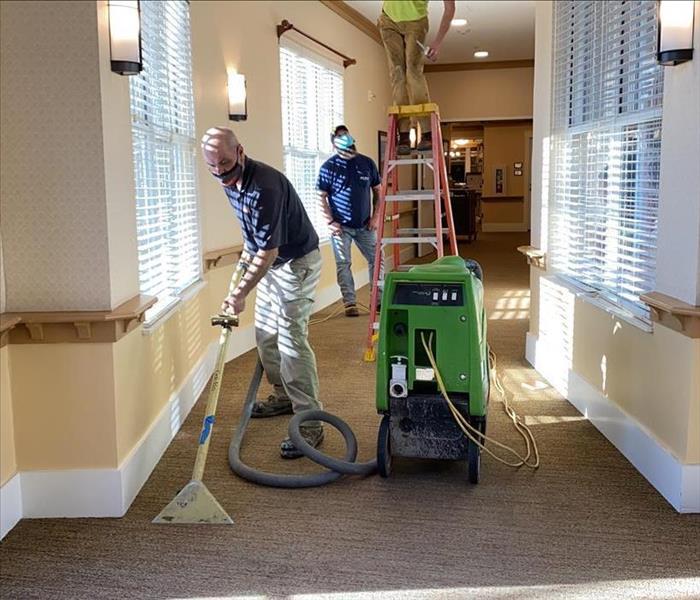 SERVPRO team members are removing water from a carpet.