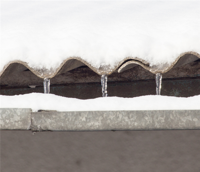Picture is a close up of a clay roof covered in ice and snow 