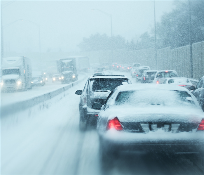 Snow covered cars make their way along a busy highway.